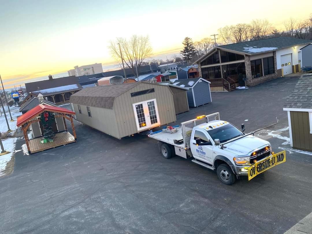 A 16x48 ft shed is being loaded onto a delivery truck.