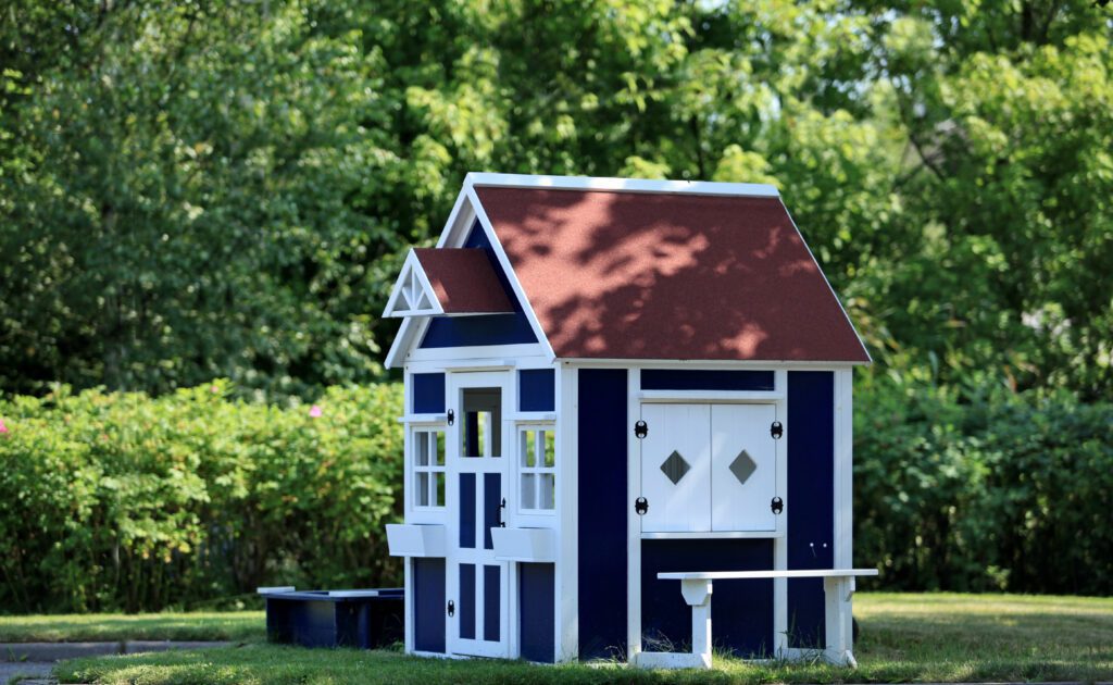 A blue and white child’s playhouse sits in the backyard.