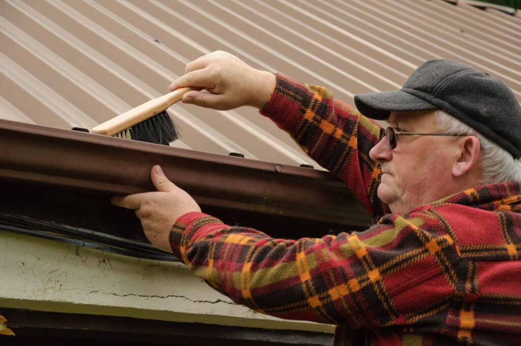 A man cleans the gutters of his shed.